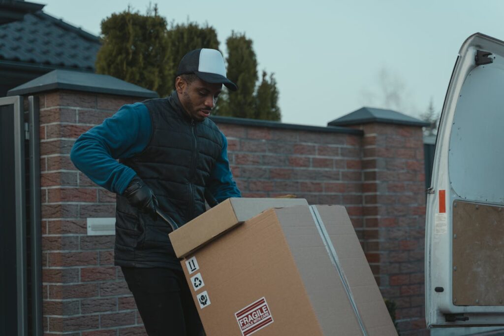 The Art of Drawing Readers In: Your attractive post title goes here Courier loading cardboard box into a van outdoors, showcasing logistics work.